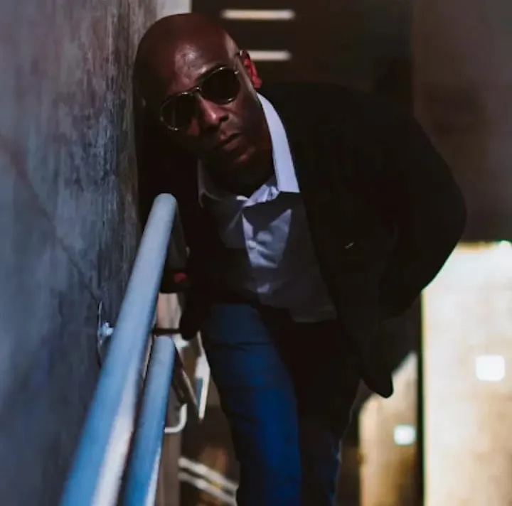 Marcus Chocollate in sunglasses on a stairway at night, leaning on the handrail.